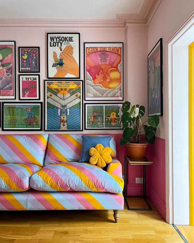 canto de sala de decoração maximalista com sofá listrado colorido e quadros na parede