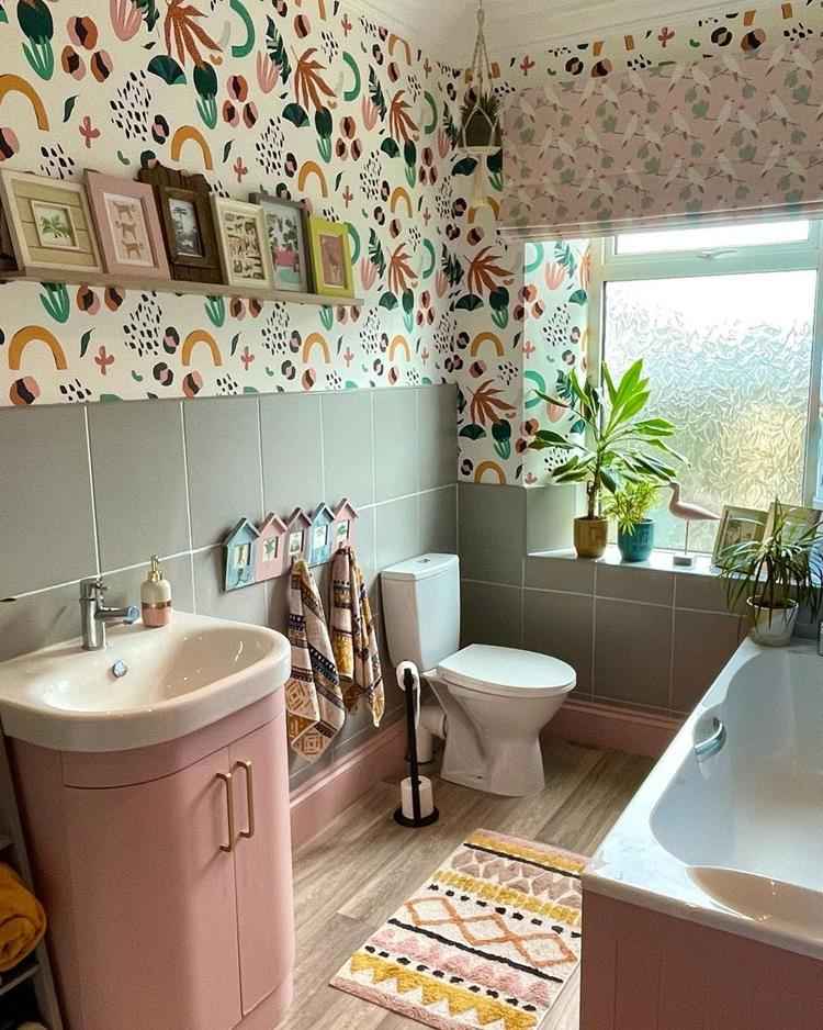 banheiro com decoração maximalista de tons claros, azulejos na cor verde e metade da parede estampada