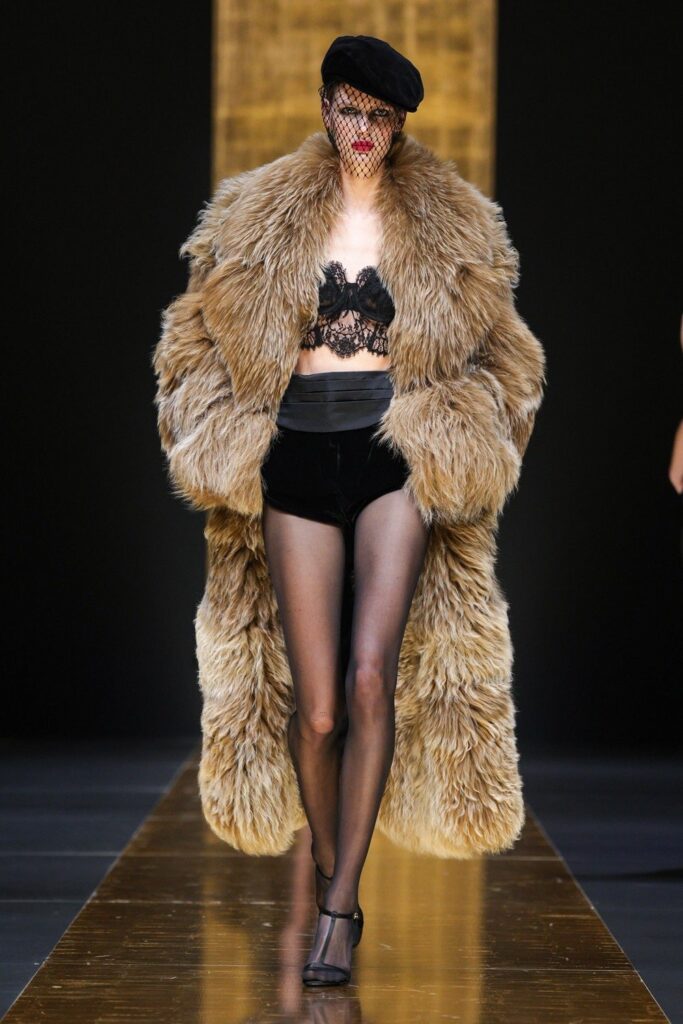 No desfile da Dolce & Gabbana, modelo usa casaco de fur com boina preta de veludo e véu rendado sobre a face.