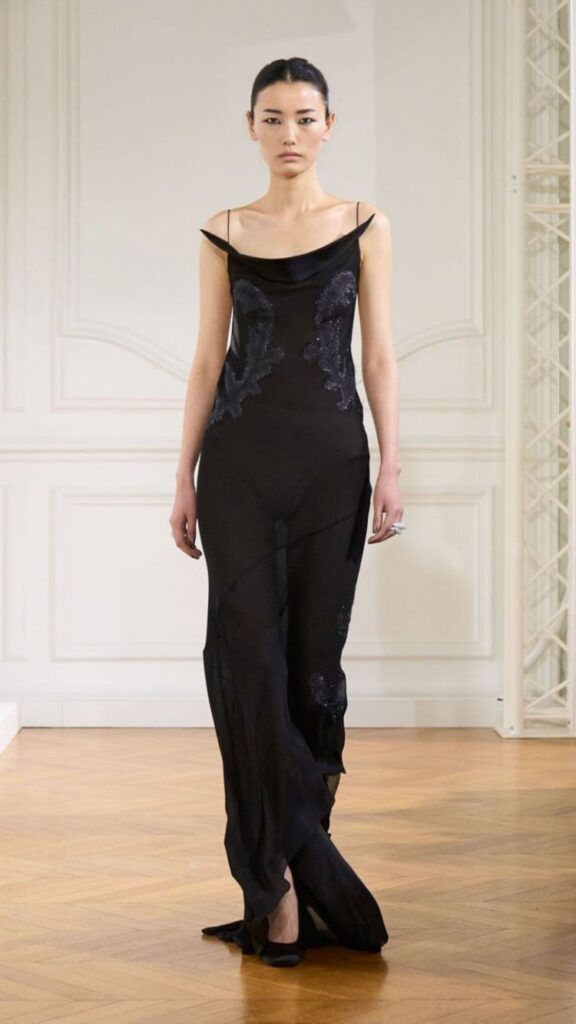 Modelo usa vestido preto com alças finas e transparência, com detalhes nas laterais, em desfile da Givenchy. 