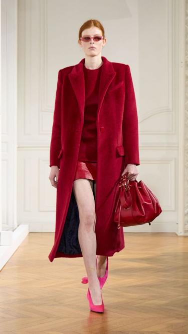 A modelo ruiva desfila para Givenchy, usando vermelho: conjunto de mini saia com casaco vermelho em veludo, e scarpin bico fino rosa. 