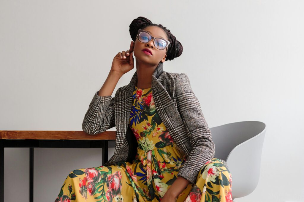 Mulher negra usando vestido de flores e paletó xadrez.