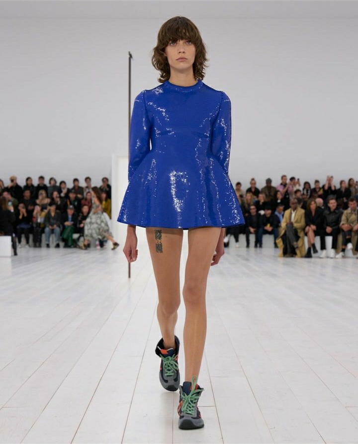 Imagem do desfile Loewe. O vestido trapézio mini deixa claro como o clássico se reinventou na passarela.