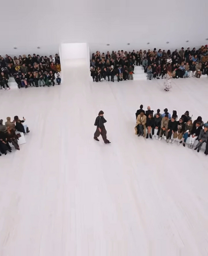 Imagem do desfile de Jonathan Anderson. O ambiente branco da passarela facilita o foco nas roupas apresentadas.