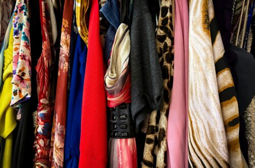 Roupas coloridas e estampadas penduradas em cabides, em um varal, exibindo diversidade de tecidos e estilos.