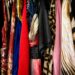 Roupas coloridas e estampadas penduradas em cabides, em um varal, exibindo diversidade de tecidos e estilos.