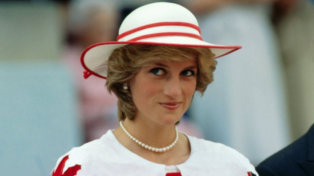 Princesa Diana com um pequeno e delicado chapéu branco com detalhes em vermelho, combinando com sua roupa que segue o mesmo padrão de cor. 

Foto registrada, provavelmente, em uma de suas aparições públicas para as ações sociais que participava.